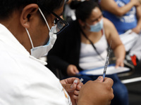 A male nurse prepares a Sputnik-V dose booster  to supply it to a person inside Sport City facilities, during the mass vaccination campaign...