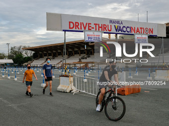 People engage in physical activities at an almost empty drive-thru vaccination site in Manila City, Philippines on February 23, 2022. Metro...