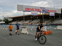 People engage in physical activities at an almost empty drive-thru vaccination site in Manila City, Philippines on February 23, 2022. Metro...