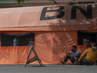 Residents wait for their families who are being treated for COVID-19 in emergency tents set up at Undata Hospital, Palu, Central Sulawesi Pr...