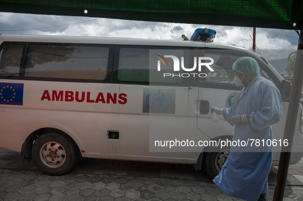 A driver sprays disinfectant liquid on an ambulance after transporting patients to an emergency tent for COVID-19 treatment which was set up...