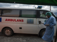 A driver sprays disinfectant liquid on an ambulance after transporting patients to an emergency tent for COVID-19 treatment which was set up...