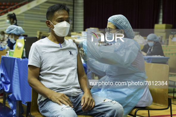 People receive doses of the Pfizer COVID-19 vaccine at a vaccination center inside a stadium in Bangkok, Thailand, 24 February 2022. 