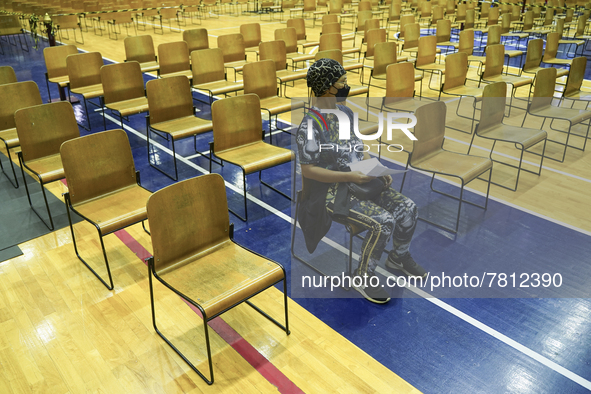 People sit and wait up to receive the COVID-19 vaccine at a vaccination center inside a stadium in Bangkok, Thailand, 24 February 2022. 