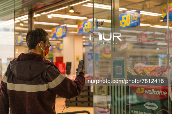 A man scans the Leave Home Safe QR code outside a supermarket, in Hong Kong, China, on February 24, 2022. As of today, it is compulsory to b...