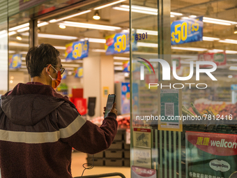 A man scans the Leave Home Safe QR code outside a supermarket, in Hong Kong, China, on February 24, 2022. As of today, it is compulsory to b...