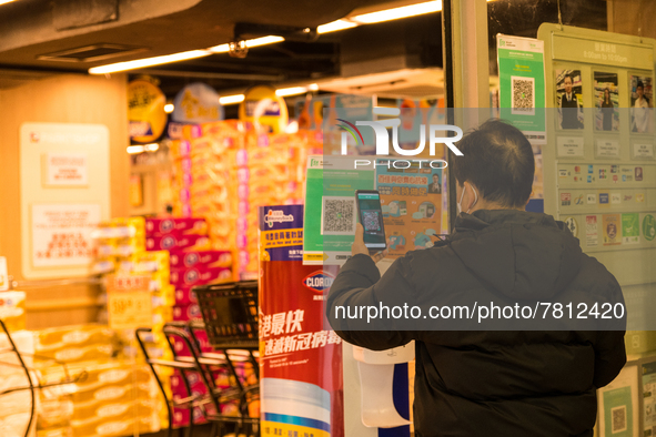 A man scans the Leave Home Safe QR code before entering a supermarket, in Hong Kong, China, on February 24, 2022. As of today, it is compuls...