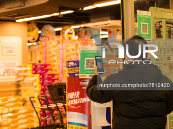 A man scans the Leave Home Safe QR code before entering a supermarket, in Hong Kong, China, on February 24, 2022. As of today, it is compuls...