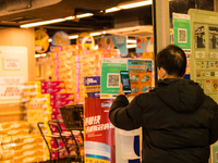 A man scans the Leave Home Safe QR code before entering a supermarket, in Hong Kong, China, on February 24, 2022. As of today, it is compuls...