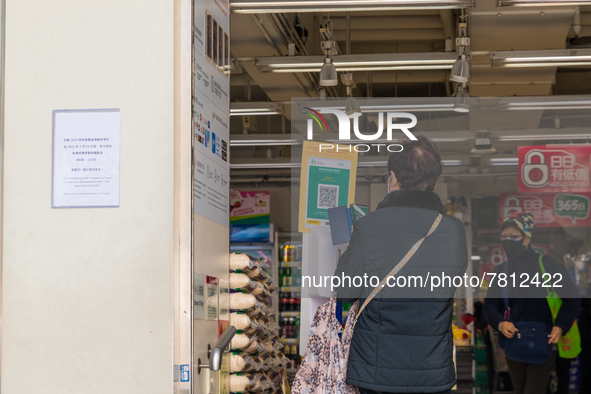 A woman scans the Leave Home Safe QR code before entering a supermarket in the Kowloon Bay area, in Hong Kong, China, on February 24, 2022....