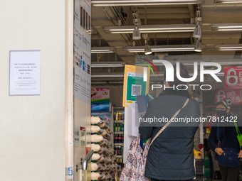 A woman scans the Leave Home Safe QR code before entering a supermarket in the Kowloon Bay area, in Hong Kong, China, on February 24, 2022....