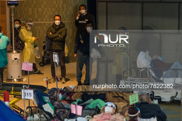 Family members and staff huddle near heaters while COVID patients are placed in beds near the entrance of the Accident & Emergency ward of C...