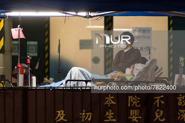 A father stands next to his wife and their child infected by COVID outside the Accident & Emergency ward of Caritas Medical Centre, in Hong...