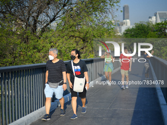 People wearing a face mask as a preventive measure against the spread of COVID-19 walk around sky walk at the Benchakitti Forest Park on Feb...