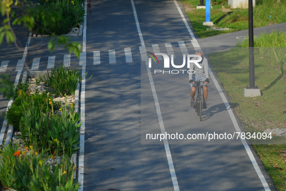 A man wearing a face mask as a preventive measure against the spread of COVID-19 rides a bicycle at the Benchakitti Forest Park on February...