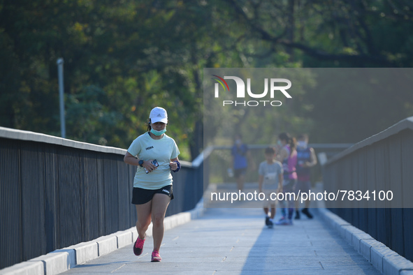 A woman wearing a face mask as a preventive measure against the spread of COVID-19 jogs around sky walk at the Benchakitti Forest Park on Fe...