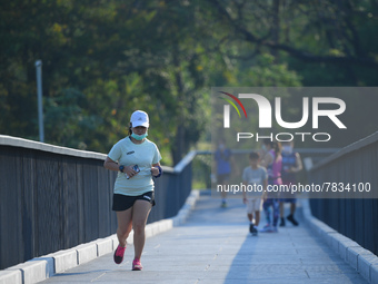 A woman wearing a face mask as a preventive measure against the spread of COVID-19 jogs around sky walk at the Benchakitti Forest Park on Fe...