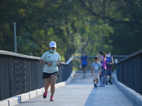 A woman wearing a face mask as a preventive measure against the spread of COVID-19 jogs around sky walk at the Benchakitti Forest Park on Fe...