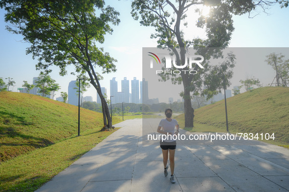 A woman wearing a face mask as a preventive measure against the spread of COVID-19 jogs around sky walk at the Benchakitti Forest Park on Fe...