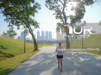 A woman wearing a face mask as a preventive measure against the spread of COVID-19 jogs around sky walk at the Benchakitti Forest Park on Fe...