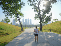 A woman wearing a face mask as a preventive measure against the spread of COVID-19 jogs around sky walk at the Benchakitti Forest Park on Fe...