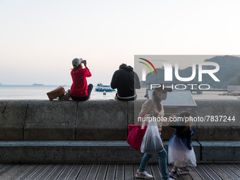 A mother and her daughter pass on Stanley promenade as a couple enjoys the sunset in Hong Kong, China, on February 27, 2022. (