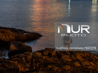 A couple takes a selfie on a rock at Stanley as night falls in Hong Kong, China, on February 27, 2022. (