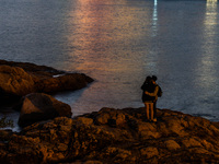 A couple takes a selfie on a rock at Stanley as night falls in Hong Kong, China, on February 27, 2022. (