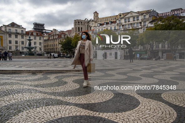 A woman wearing a protective mask is seen walking around Praça de Rossio, Lisbon. February 20, 2022. The Portuguese General Health Direction...