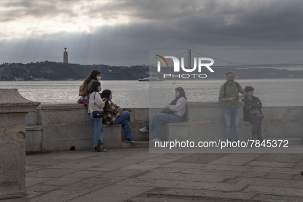 People wearing protective masks are seen resting on the banks of the Tejo river, in the Cais das Colunas area, Lisbon. February 20, 2022. Th...