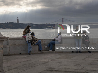 People wearing protective masks are seen resting on the banks of the Tejo river, in the Cais das Colunas area, Lisbon. February 20, 2022. Th...