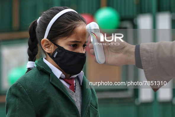 An employee checks the temperature of a student at the entrance of Baramulla public school in Baramulla Jammu and Kashmir India on 02 March...