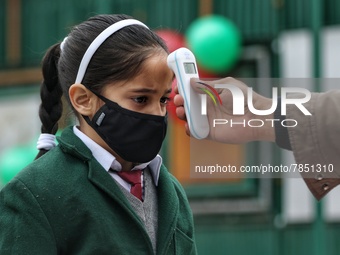 An employee checks the temperature of a student at the entrance of Baramulla public school in Baramulla Jammu and Kashmir India on 02 March...