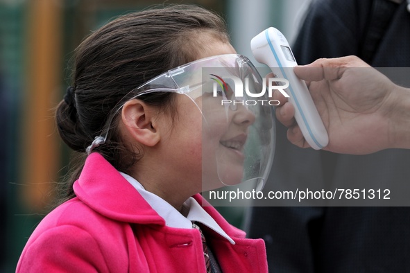 An employee checks the temperature of a student wearing shield at the entrance of Baramulla public school in Baramulla Jammu and Kashmir Ind...