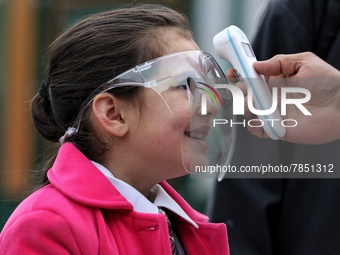 An employee checks the temperature of a student wearing shield at the entrance of Baramulla public school in Baramulla Jammu and Kashmir Ind...