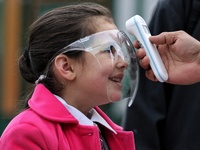 An employee checks the temperature of a student wearing shield at the entrance of Baramulla public school in Baramulla Jammu and Kashmir Ind...