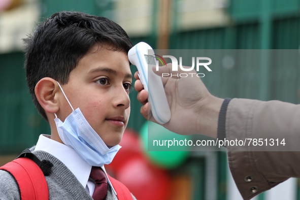 An employee checks the temperature of a student at the entrance of Baramulla public school in Baramulla Jammu and Kashmir India on 02 March...