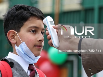 An employee checks the temperature of a student at the entrance of Baramulla public school in Baramulla Jammu and Kashmir India on 02 March...