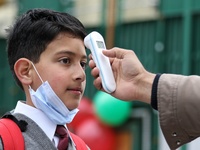 An employee checks the temperature of a student at the entrance of Baramulla public school in Baramulla Jammu and Kashmir India on 02 March...