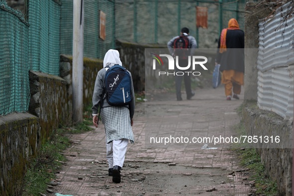 A student leaves her home for school in Baramulla Jammu and Kashmir India on 02 March 2022. An employee checks the temperature of a student...