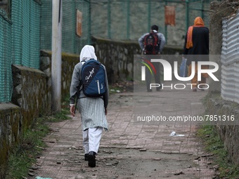 A student leaves her home for school in Baramulla Jammu and Kashmir India on 02 March 2022. An employee checks the temperature of a student...