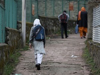 A student leaves her home for school in Baramulla Jammu and Kashmir India on 02 March 2022. An employee checks the temperature of a student...