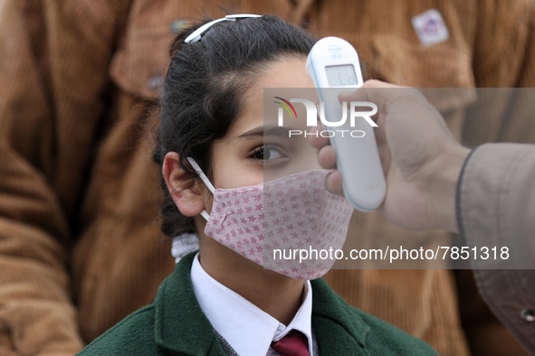 An employee checks the temperature of a student at the entrance of Baramulla public school in Baramulla Jammu and Kashmir India on 02 March...