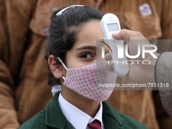 An employee checks the temperature of a student at the entrance of Baramulla public school in Baramulla Jammu and Kashmir India on 02 March...