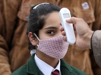 An employee checks the temperature of a student at the entrance of Baramulla public school in Baramulla Jammu and Kashmir India on 02 March...