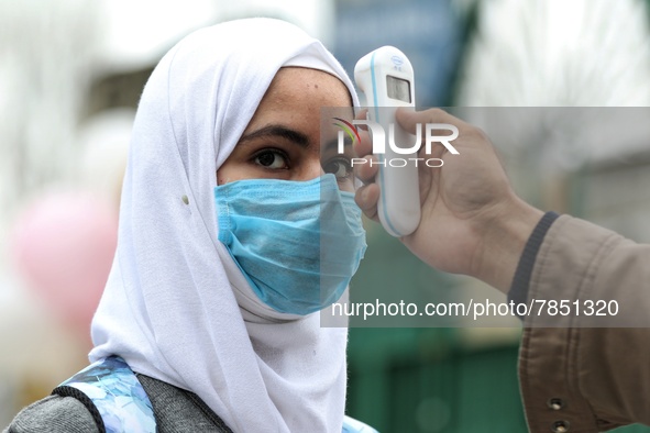 An employee checks the temperature of a student at the entrance of Baramulla public school in Baramulla Jammu and Kashmir India on 02 March...