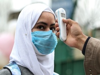 An employee checks the temperature of a student at the entrance of Baramulla public school in Baramulla Jammu and Kashmir India on 02 March...