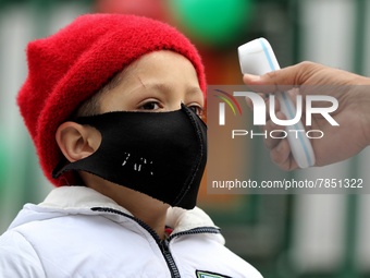 An employee checks the temperature of a student at the entrance of Baramulla public school in Baramulla Jammu and Kashmir India on 02 March...