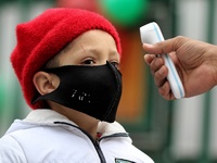 An employee checks the temperature of a student at the entrance of Baramulla public school in Baramulla Jammu and Kashmir India on 02 March...