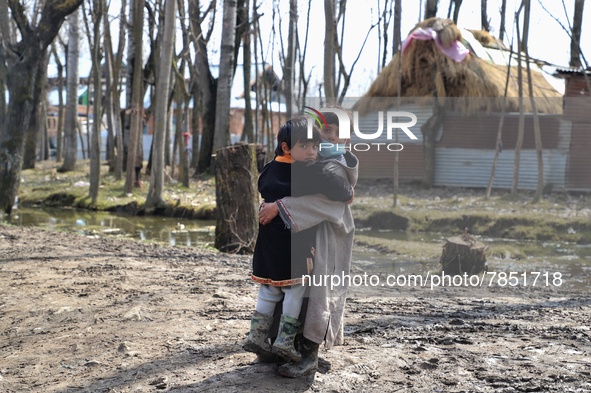 A boy carries her sister through a muddy road in Sopore district Baramulla Jammu and Kashmir India on 02 March 2022. 